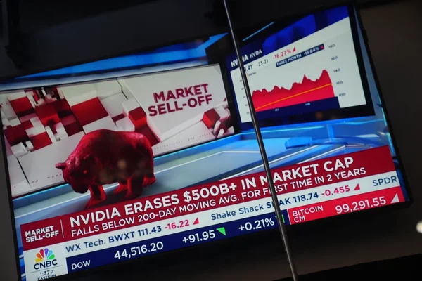 Television screens showing market charts and an Nvidia sell-off headline
