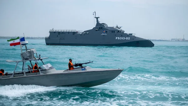 A patrol boat with an Iranian flag beside a larger vessel