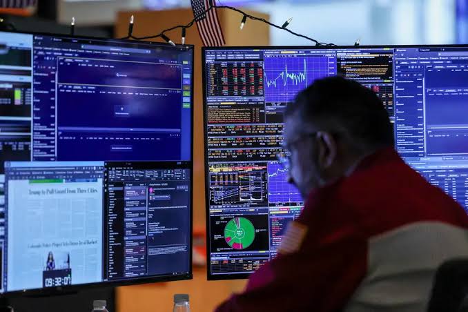 Analyst monitoring financial markets across multiple trading screens.